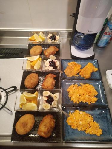 a table with four trays of different types of food at Auberge du Tanuki Noir Maison d'Hôtes in Osaka