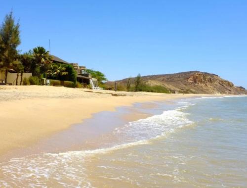 a sandy beach with a house and the ocean at Maison Popenguine sur Mer in Poponguine