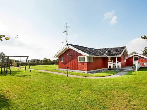 a red house with a playground in the yard at Seaside Bliss in Kelstrup - By Traum Ferienwohnungen in Slagelse