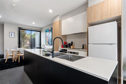 a kitchen with a sink and a white refrigerator at Modern 3-Bedroom Townhouse in Quiet Greenway in Tuggeranong