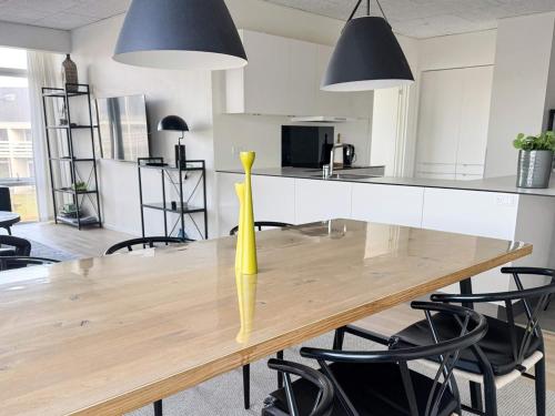 a dining room table with a yellow vase on it at 8 person holiday home in Ringkøbing in Ringkøbing