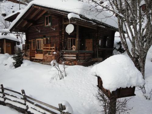 a log cabin in the snow with a fence at Neukam Hütte in Mühlbach am Hochkönig