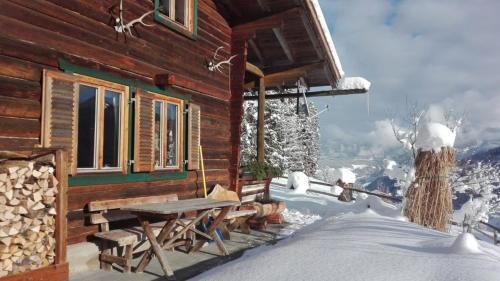 a log cabin with a picnic table in the snow at Neukam Hütte in Mühlbach am Hochkönig