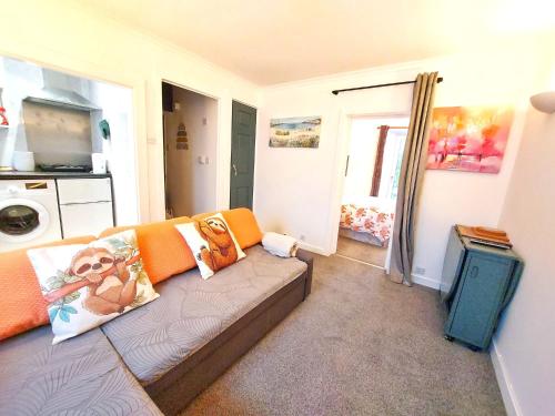 a living room with a couch with orange pillows at The Wee Nest in Largs - One-Bedroom Ground Flat in Largs
