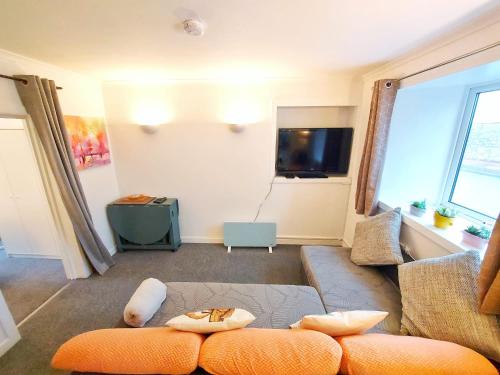 a living room with a couch and a tv at The Wee Nest in Largs - One-Bedroom Ground Flat in Largs