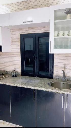 een keuken met een wastafel en een zwarte magnetron bij Modern Stay in Nouakchott