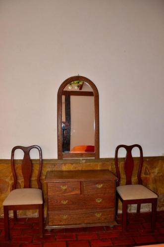 a dresser with two chairs and a mirror at Posada Guasu in Samaipata