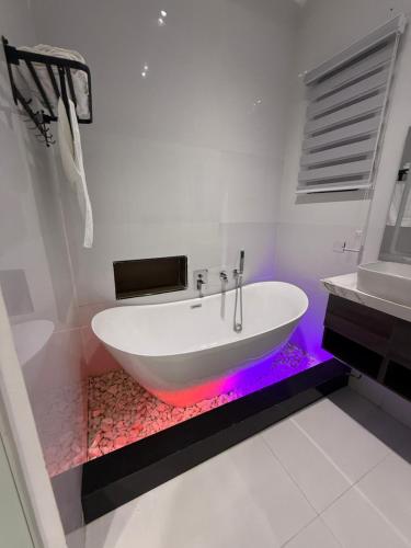 Un baño blanco con una bañera con luz morada en ZELE homes, en Aja