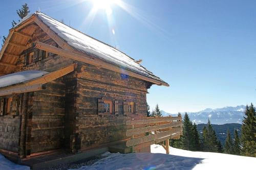 a log cabin in the snow with the sun behind it at Alpine-Lodges Lisa in Hintersauerwald