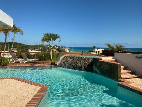 a swimming pool with a waterfall and the ocean at Family Beach House with an Amazing Ocean View in Naguabo
