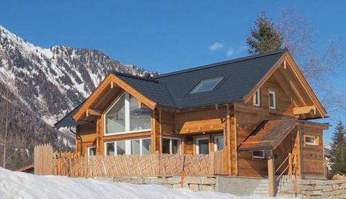 a log cabin with a black roof in the snow at Chalet Alteck in Rauris