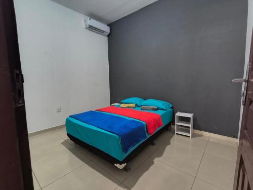 Schlafzimmer mit einem Bett mit blauer und roter Bettwäsche in der Unterkunft Casa Altos COP30, Next to the Hangar in Belém