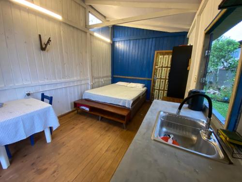 een keuken met een wastafel en een bed in een kamer bij Cabana da palmeira in Piçarras