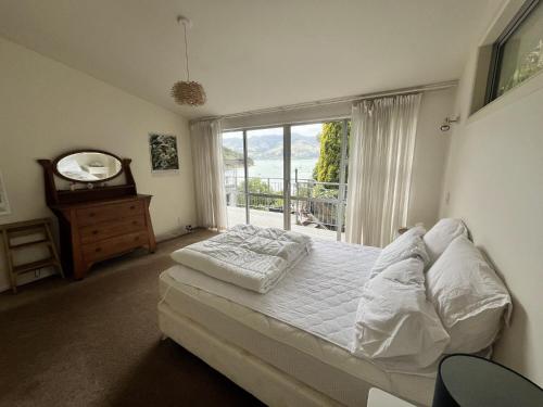 a bedroom with a bed and a large window at Beachfront Tranquility in Tikao Bay in Wainui