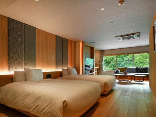 a hotel room with two beds and a living room at HanaMOMIJI in Jozankei