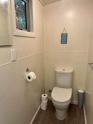 a small bathroom with a toilet and a window at Beachfront Tranquility in Tikao Bay in Wainui