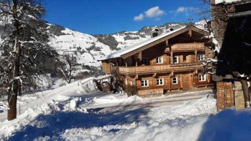 a large wooden cabin in the snow with trees at Bauernhaus Brixen in Bichling
