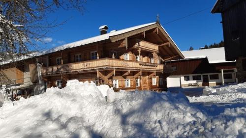 a large building with a pile of snow in front of it at Bauernhaus Brixen in Bichling