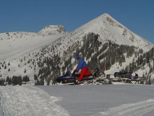 a man is sitting on a snowboard in the snow at Lockner Hütte in Schwaigs