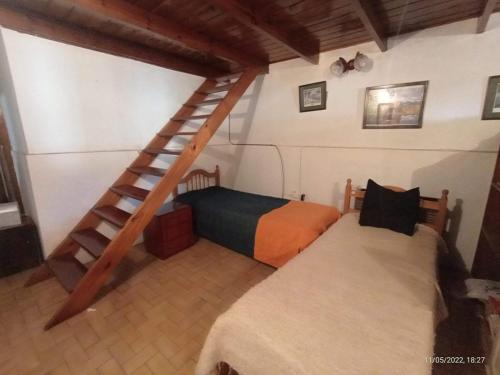 a bedroom with two beds and a wooden staircase at Casa En Necochea 6 personas in Necochea