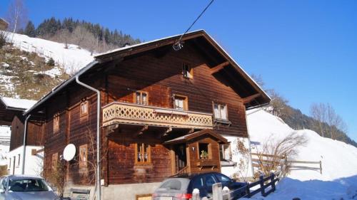 a log cabin in the snow with cars parked in front at Schmaranzhütte in Grossarl