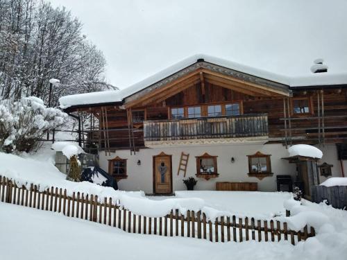 ein Blockhaus im Schnee mit einem Zaun in der Unterkunft Almchalet Schneeberg in Mühlbach am Hochkönig
