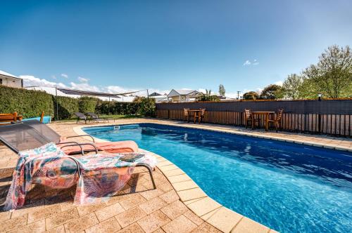 a swimming pool with two chairs and a table next to it at Panorama Hotel St Helens in St Helens