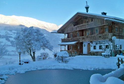 a large wooden building covered in snow next to a pond at Bergchalet Klausner Edelweiß in Ramsberg