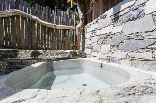 a hot tub in a stone wall with a fence at Chalet Wildberg in Unterberg