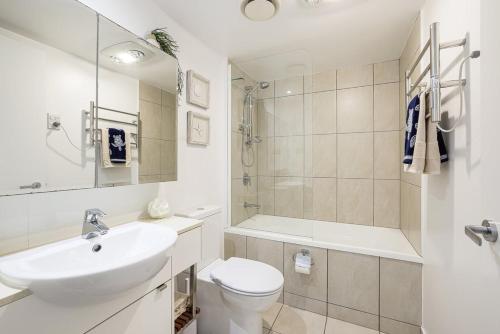 een witte badkamer met een wastafel en een toilet bij Dwell at 38, Oceanfront Apartment in Bargara