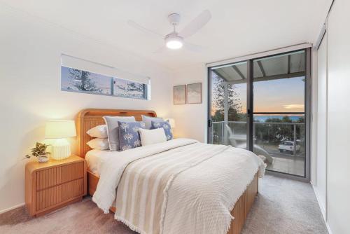 een slaapkamer met een bed en een groot raam bij Dwell at 38, Oceanfront Apartment in Bargara