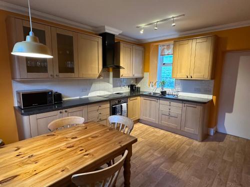 a kitchen with a wooden table with chairs and a wooden tableablish at Cosy Cottage on the Whisky Trail in Haugh of Glass