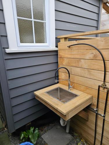 a sink sitting on the side of a house at Zen Cabin in Mount Maunganui