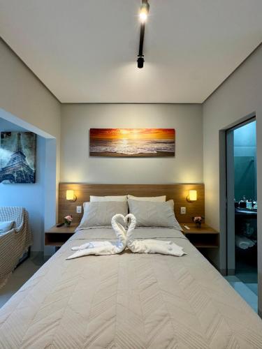 Una cama blanca grande con una toalla. en Studio aconchegante com garagem privativa e varanda, en Montes Claros