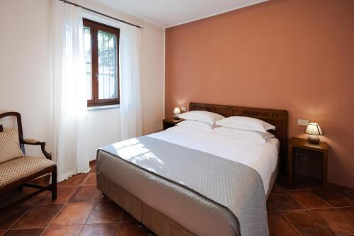 um quarto com uma cama, uma cadeira e uma janela em Casa Nizza D'Oro em Castelnuovo