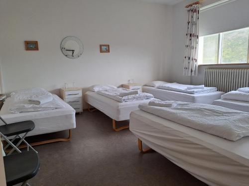 ein Zimmer mit drei Betten, einem Stuhl und einem Fenster in der Unterkunft Studlagil INN Hostel in Skjöldólfsstaðir