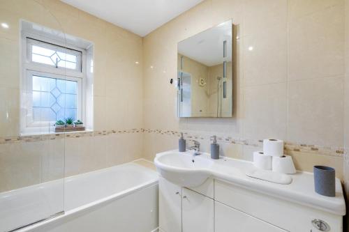 a white bathroom with a sink and a mirror at Isher 3 Bedroom, 2-Bathroom House with Parking in Uxbridge