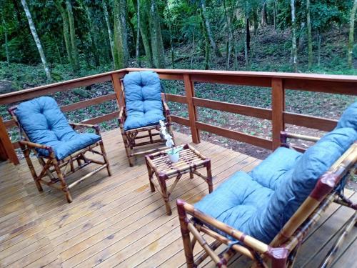 three chairs and a table on a deck at Cabana Encanto da Mata in Santa Maria do Erval