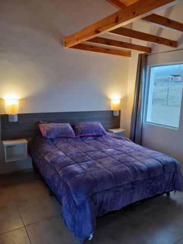 a bedroom with a bed with a blue comforter at Cielo in Tafí del Valle