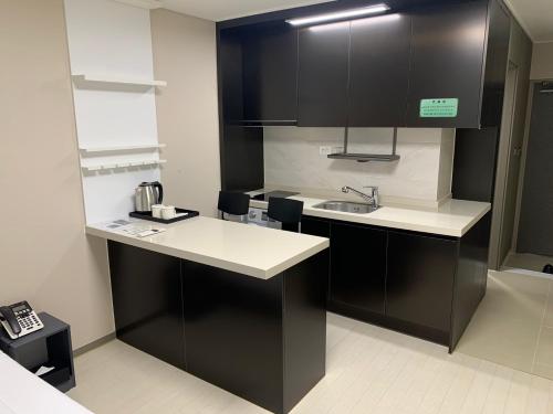 a kitchen with black cabinets and a sink at 강릉 하이오션 경포 a203 in Gangneung