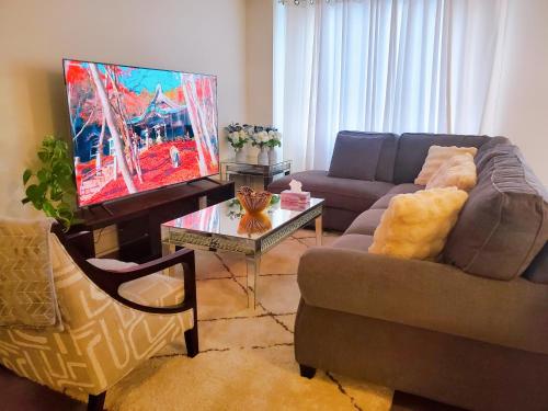 a living room with a couch and a flat screen tv at New 3-BR Home Near Niagara Falls with King Bed 75 Inch TV and Free Parking in Thorold
