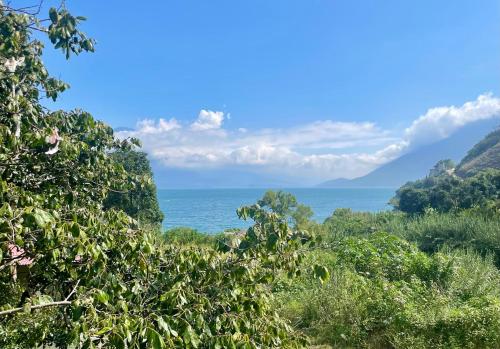 a view of the ocean from behind trees at EB5 Escape Tzununa, Lake Atitlan Room #1 - two minute walk to the Lake in Santa Cruz La Laguna