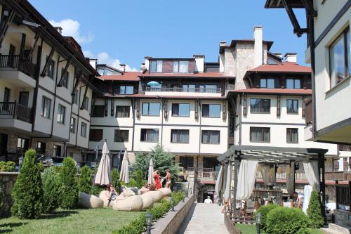 un hotel con personas sentadas bajo sombrillas en un patio en Maria-Antoaneta Residence en Bansko