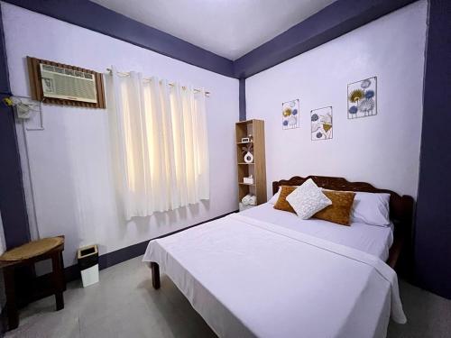 a bedroom with a white bed and a window at 88 Tourist Inn by Lagum Adventure in Coron