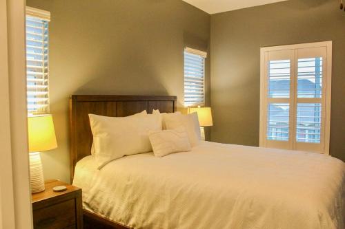 a bedroom with a bed with white sheets and two windows at The Pensacola Retreat-Spacious, pet-friendly home in Pensacola