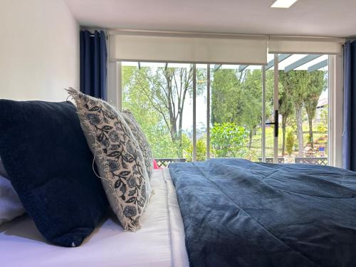 een slaapkamer met een bed met kussens en een raam bij Suite de lujo con naturaleza y BBQ cerca de Cuenca in Cuenca