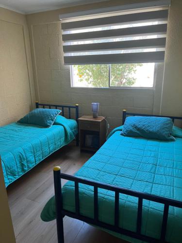 two beds in a room with a window at Elqui Antu in Vicuña