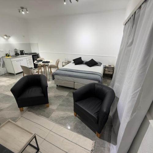 a bedroom with a bed and two black chairs at Espacio Uno B in Belén de Escobar