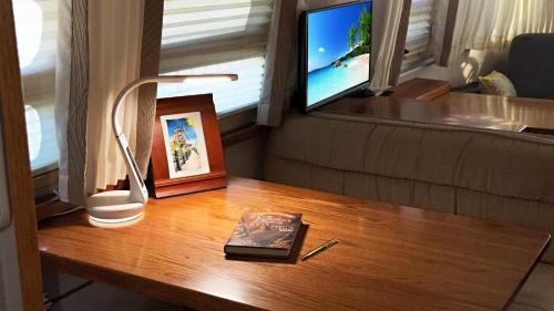 a table with a book and a lamp and a television at Retro Star-Wagon, Ocean View at Studios in Oceanside