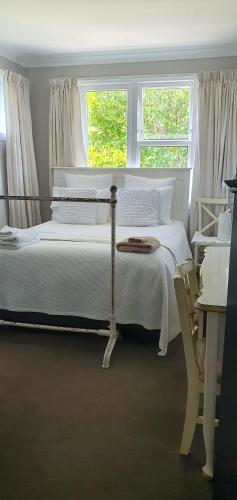 ein weißes Bett in einem Zimmer mit 2 Fenstern in der Unterkunft Dragonflycottagebnb in Grovetown